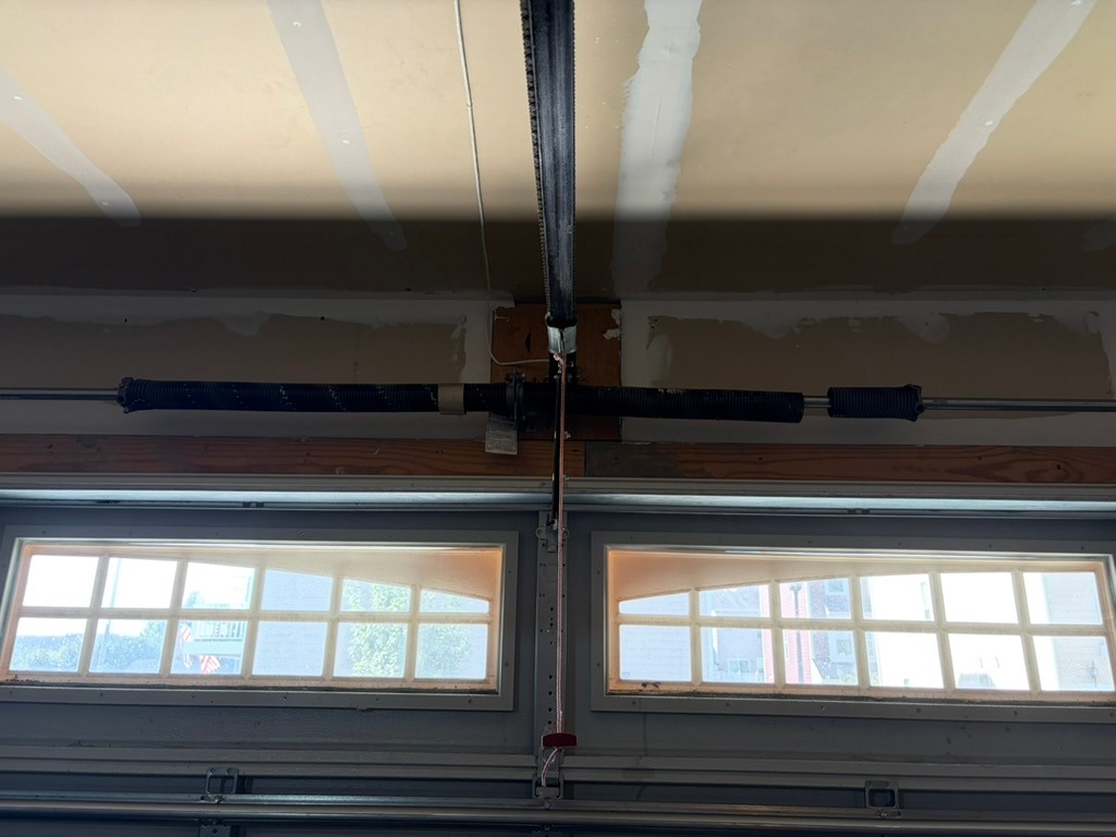 Garage door opener arm, rail and emergency release cord above a sectional door